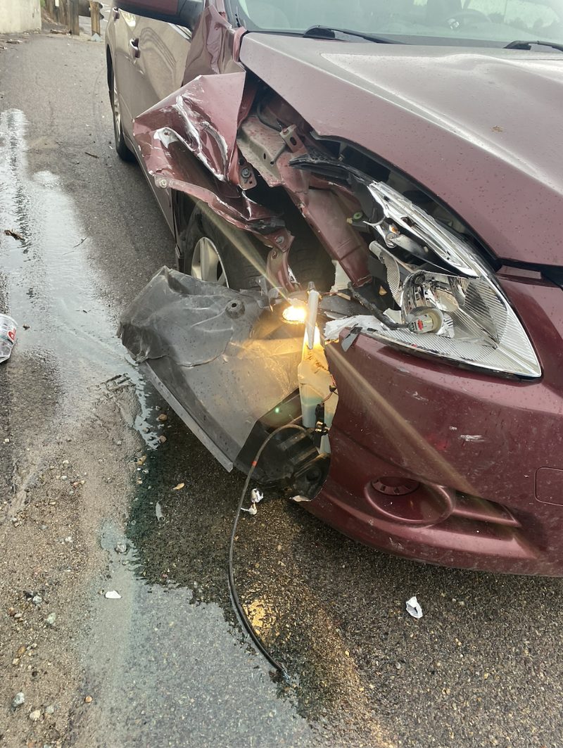 Collision damage on the front of a maroon sedan at the shop